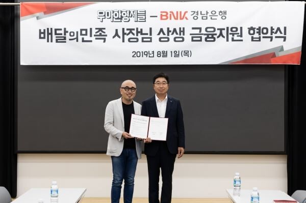 ▲우아한형제들 김봉진대표(좌)와 BNK경남은행 황윤철은행장(우)이 송파구 우아한형제들 본사에서 ‘배달의민족 사장님 상생 금융 지원 협약’ 체결 후 기념사진을 촬영하고 있다. [사진=우아한형제들]
