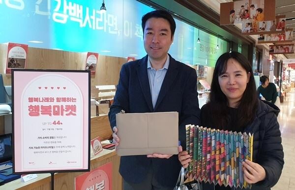 사회적기업 전용 유통플랫폼을 운영하는 아트임팩트 송윤일 대표(좌)와 행복나래 SE마케팅팀 백수정 과장(우)이 ‘행복마켓’ 팝업 스토어를 방문해 판매 제품을 선보이고 있다. (사진제공=SK이노베이션)