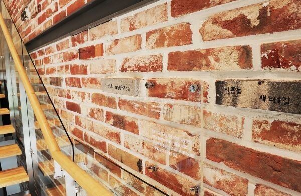SK건설은 이 달 개관 예정인 대전 ‘신흥 SK뷰(SK VIEW)’ 견본주택에 홀로그램과 가상현실(VR) 기술을 적용하고, 철거 중 발생한 폐자재를 견본주택의 마감자재와 소품으로 재활용했다. 사진은 신흥3 재개발구역 내 담장에 사용됐던 벽돌로 꾸민 신흥 SK뷰 견본주택 내부계단 측벽의 모습.[사진제공=SK건설]