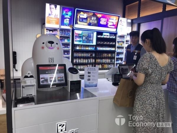 ▲세븐일레븐의 푸드특화 매장 푸드드림에서 이용자가 계산하는 모습. 계산대 왼쪽에 북극곰 모형의 무인계산대가 설치되어 있다. [사진=김자혜 기자]