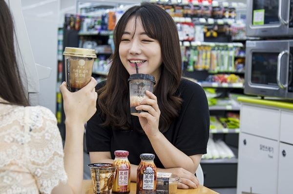 ▲한 고객이 편의점 CU에서 흑당 관련 상품을 즐기고 있다. [사진=BGF리테일]