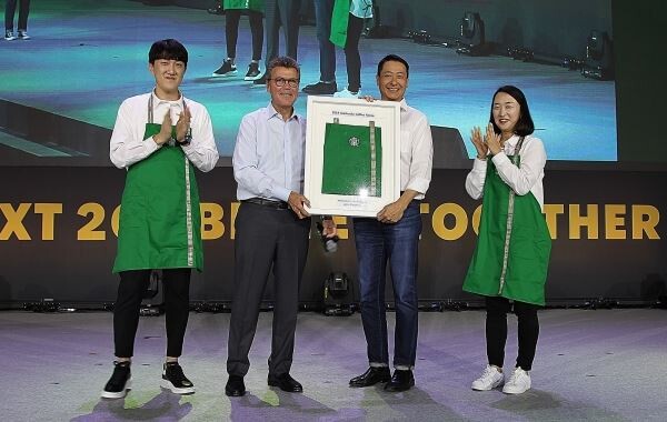 ▲지난 10일 일산 킨텍스에서 '스타벅스 코리아 리더십 컨퍼런스'에서 존 컬버 스타벅스 글로벌 총괄 사장(사진 왼쪽 2번째)이 스타벅스커피 코리아 송호섭 대표이사(사진 왼쪽 3번째)에게 커뮤니티 스토어를 상징하는 녹색 앞치마를 전달하고 있다. [사진=스타벅스코리아]